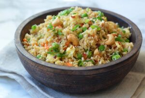Bowl of couscous with broccoli and chickpeas on a textured background.