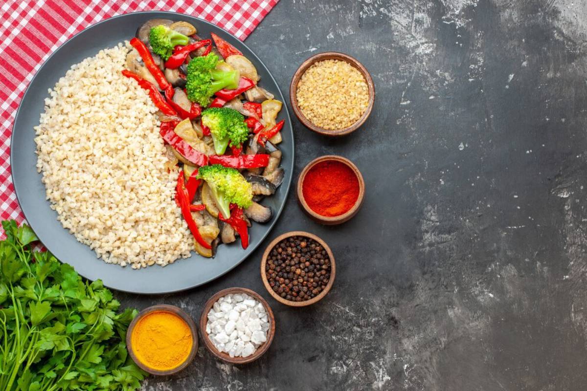 A healthy meal of brown rice and stir-fried vegetables with spices on a dark slate background.