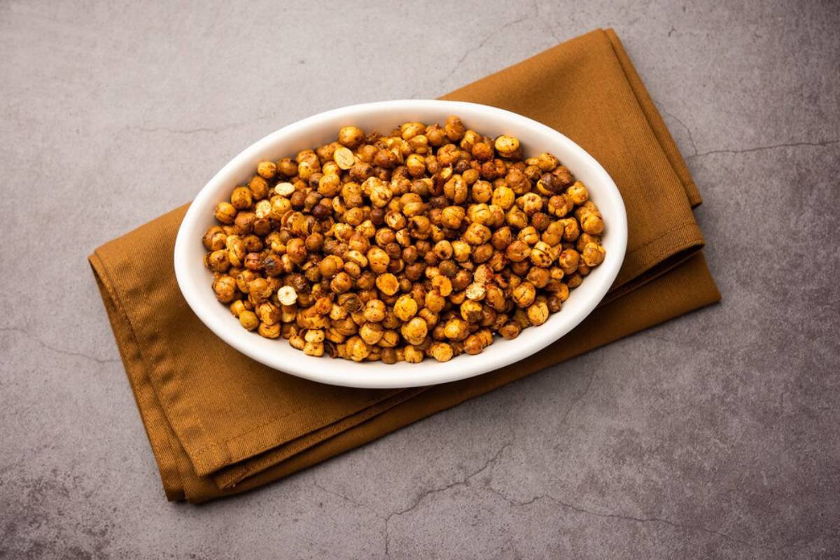 A bowl of roasted chickpeas on a brown napkin and grey background.