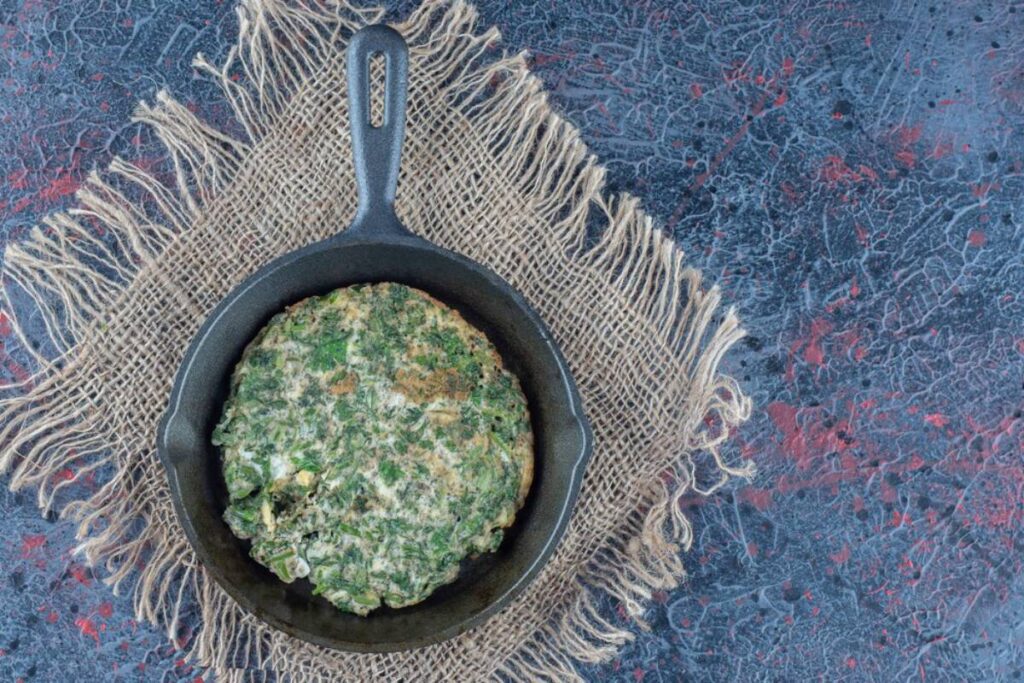 Spoon lifting creamy chickpeas and spinach from a skillet, highlighting the rich and comforting texture.