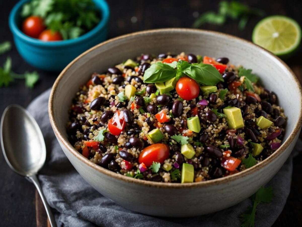 A vibrant quinoa salad with black beans, avocado, cherry tomatoes, and fresh herbs in a ceramic bowl.