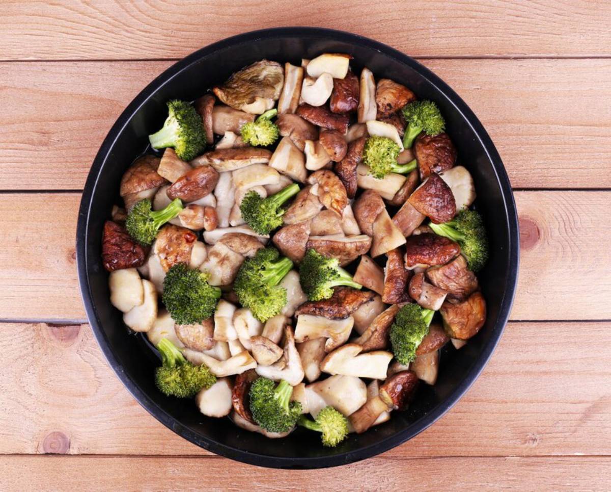 Overhead view of tofu, mushrooms, fried egg, and roasted peanuts arranged around a bowl of stir-fry, illustrating optional variations
